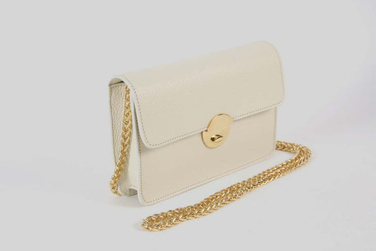 Small offwhite handbag with a golden strap.